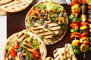 Pesto Veggie Gyros on wooden platter with grilled chicken and kabobs